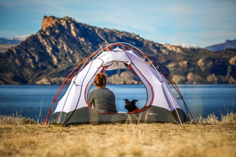 Homme dans une tente avec vue sur lac et montagne